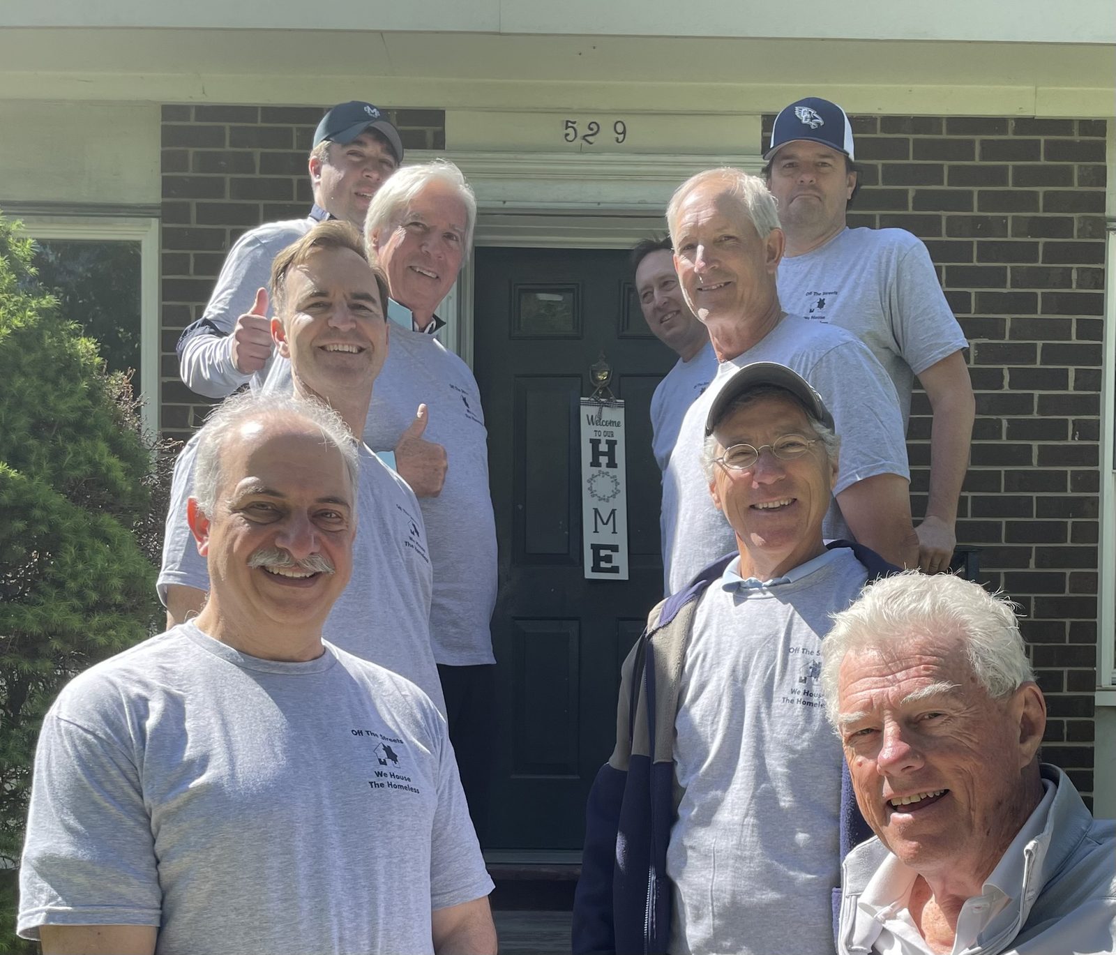The OTS Rockville volunteer crew gathered on a front porch in matching gray t-shirts