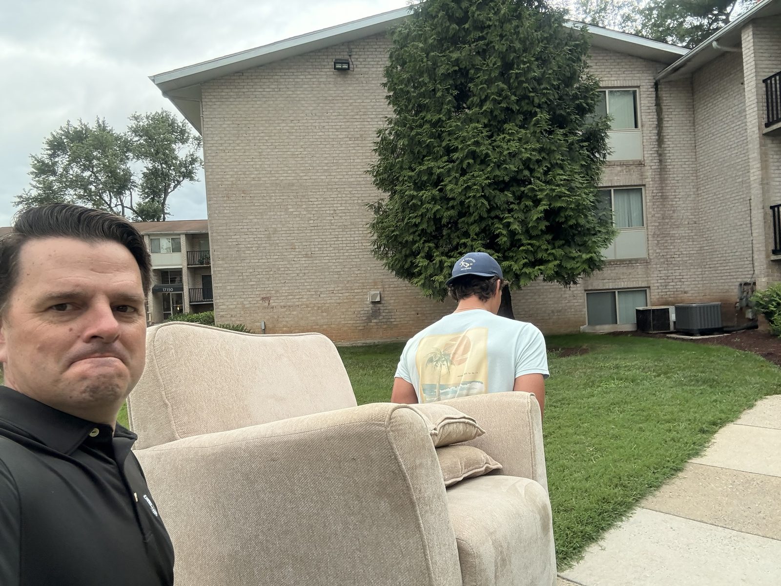 An OTS Rockville volunteer carrying an upholstered chair toward an apartment building